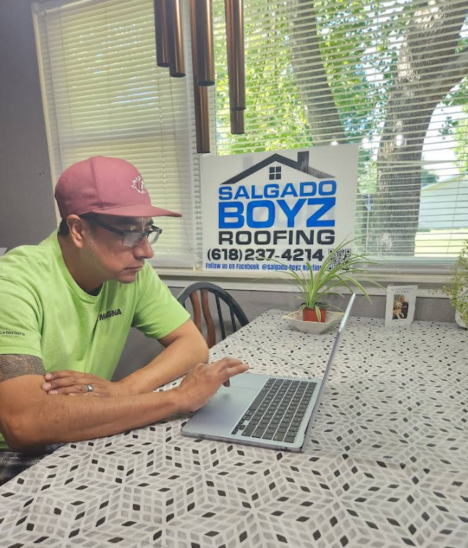 Salgado Boyz Roofing representative working beside the company's roofing sign